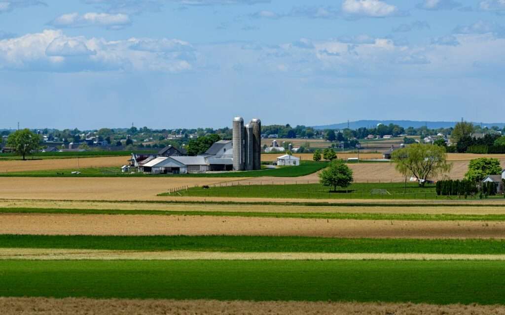 Rolling farmland with silos and a white farmhouse in Amish country, Lancaster County